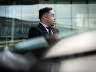 Private chauffeur Gilberto Jr. from Washington, D.C. waiting outside his vehicle.