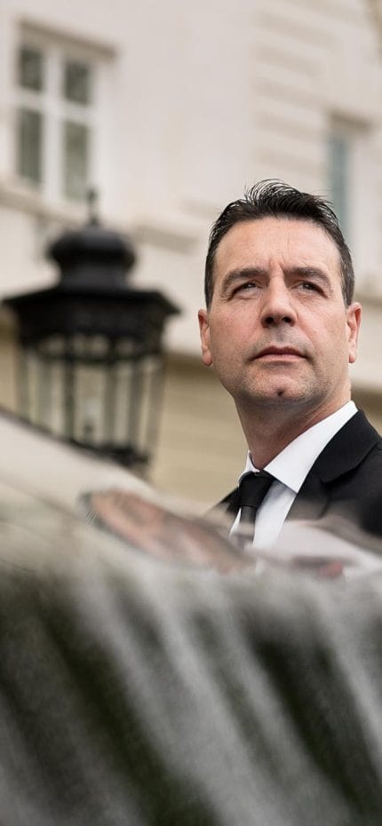 Close do motorista particular Rodrigo, de Madri, esperando do lado de fora de seu veículo.