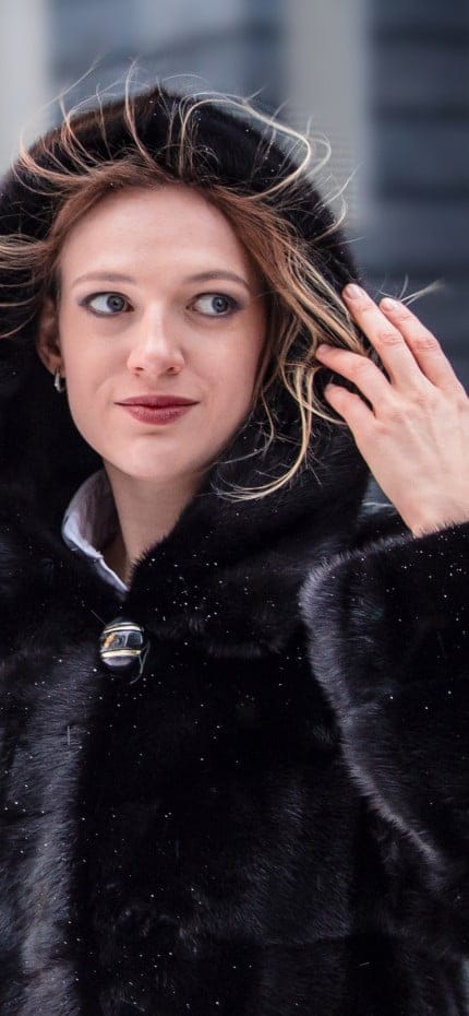 Uma garota com um casaco preto em um clima frio no centro comercial da cidade.