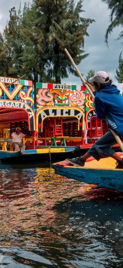 Xochimilco, Mexico City, June 25, 2019 - Young trajinero leads and rows the trajinera into Xochimilco canal.