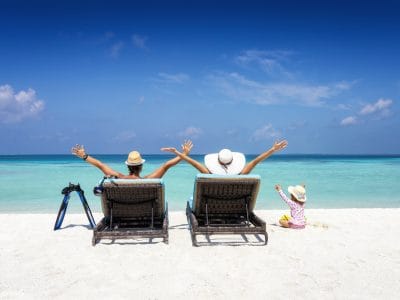 Familia feliz en tumbonas disfruta de sus vacaciones en una playa tropical con océano turquesa y sol