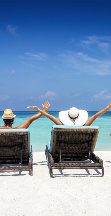 Familia feliz en tumbonas disfruta de sus vacaciones en una playa tropical con océano turquesa y sol
