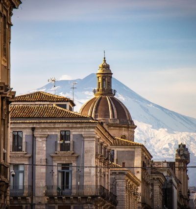 sicilian city Catania with snow capped Etna in background. Sicily, Europe, View of famous street "Via Etnea"