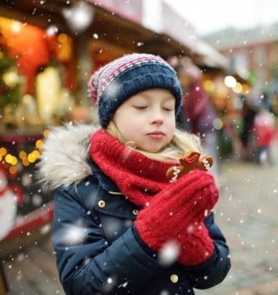 Menina bonita comendo biscoito de gengibre na tradicional feira de Natal em Riga, Letônia.