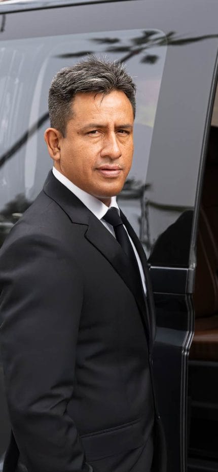 O motorista particular Cesar, de Lima, em pé ao lado de seu veículo.