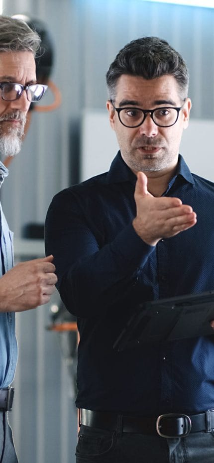 Dois homens em pé conversando sobre negócios.