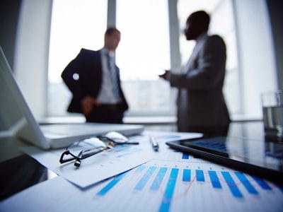 Dois homens de negócios conversando ao fundo em um ambiente de negócios.