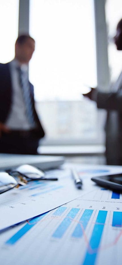 Dois homens de negócios conversando ao fundo em um ambiente de negócios.