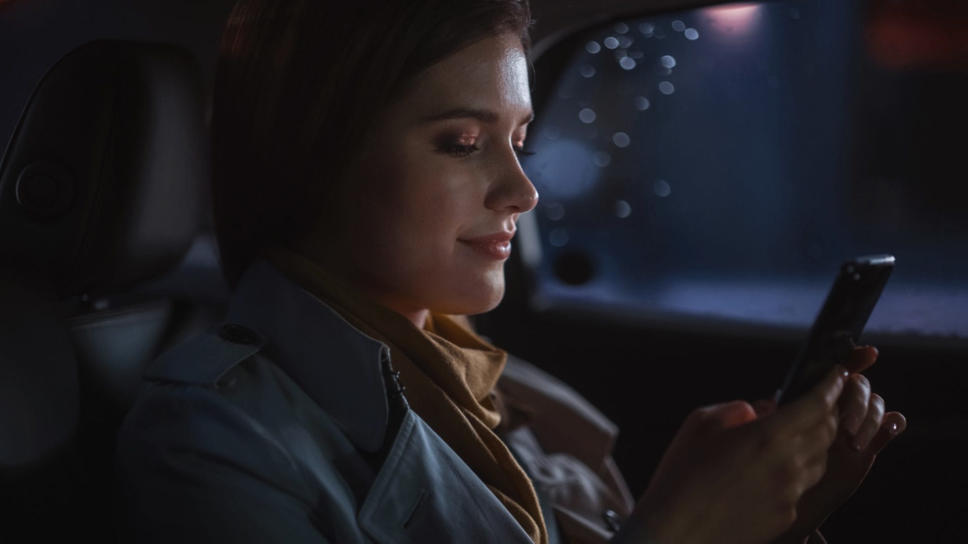Lady traveling in a corporate car at night.