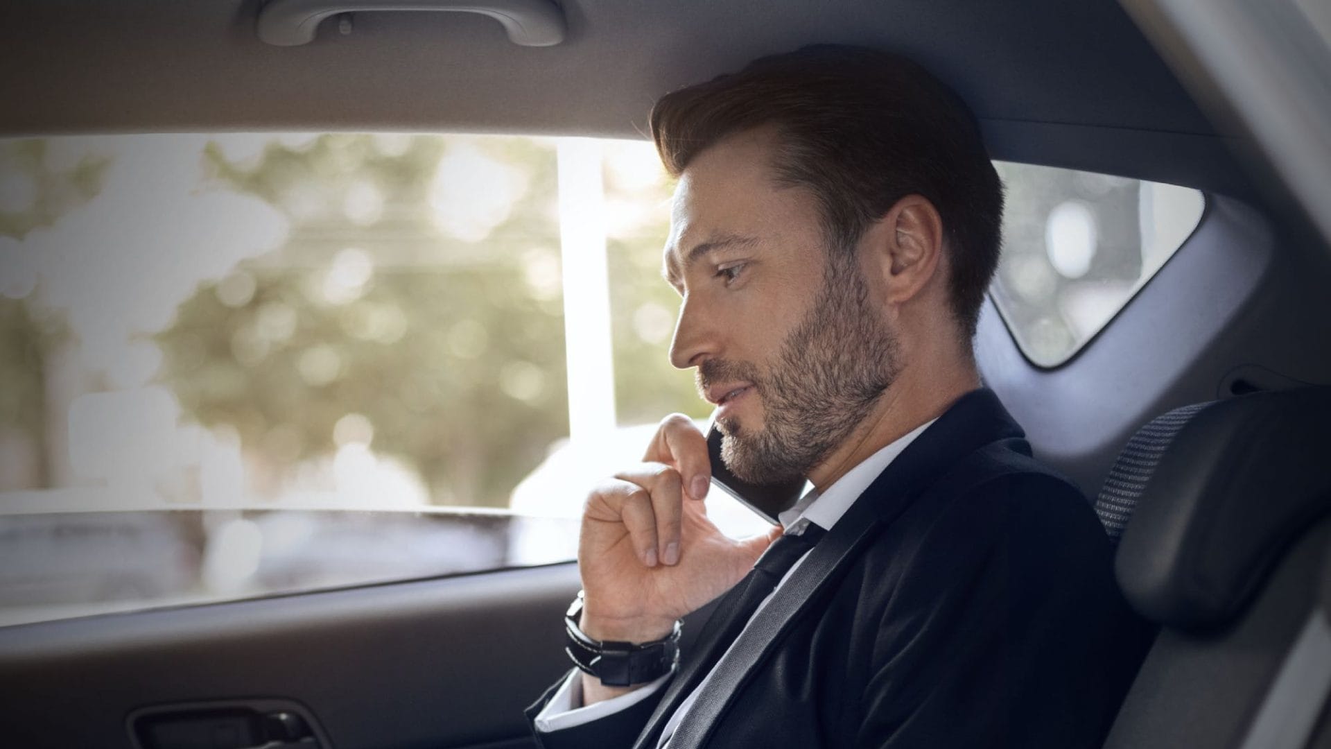 Businessman thinking while traveling in the backseat of a corporate vehicle.