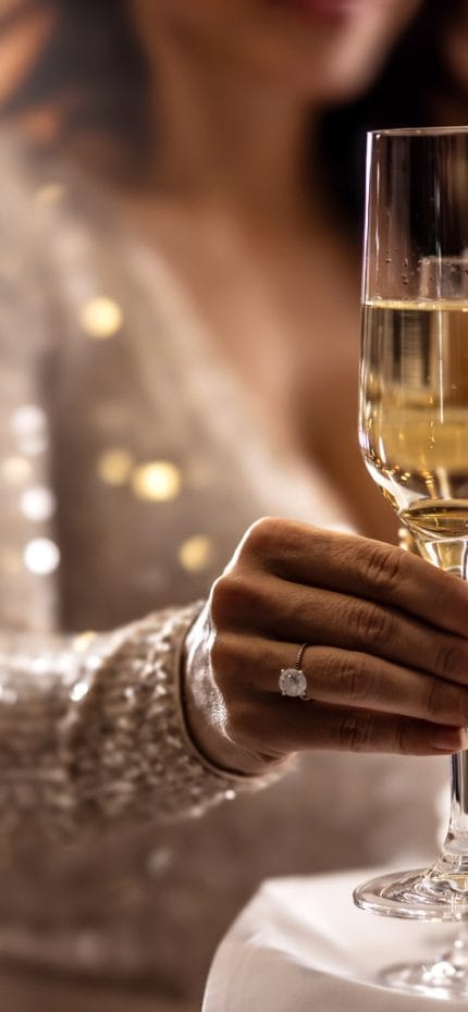 Senhora da alta sociedade segurando uma taça de champanhe.