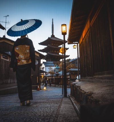 Woman in traditional japanese attire walking through a Japanese city.
