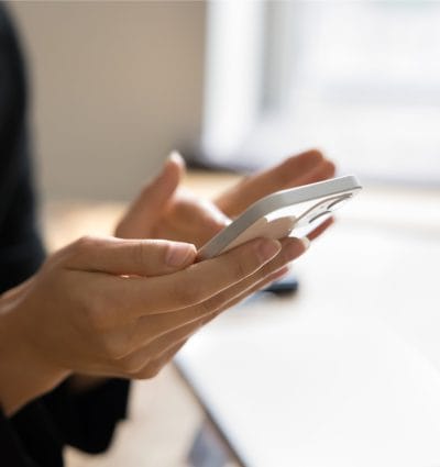 Close up shot of female hands holding smartphone. Young business woman using online application, service for communication, browsing Internet on mobile phone. Cropped shot