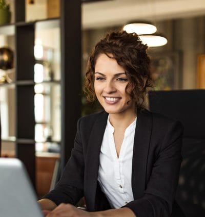 Smiling woman using laptop at work, in luxurious office, portrait.