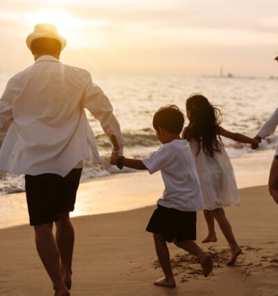 Happy asian family enjoy the sea beach at consisting father, mother,son and daughter having fun playing beach in summer vacation on the ocean beach. Happy family with vacations time lifestyle concept.