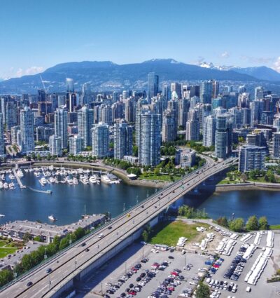 A sunny aerial shot from mid-2020 of downtown Vancouver, Yaletown, a marina, the North Shore Mountains, BC Place, False Creek, and the Cambie Bridge.