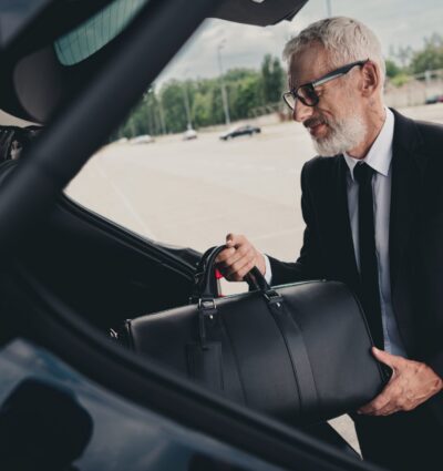 chofer privado cargando el equipaje de un pasajero en el maletero del vehículo.