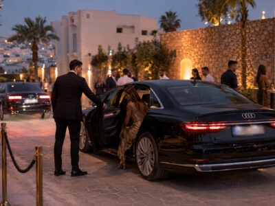 A luxury vehicle dropping off a young woman at the entrance to a private party in Ibiza.